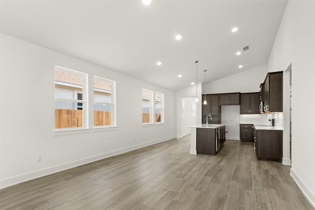 1117 Yaupon Holly Dr, Georgetown, TX 78628 - kitchen featuring light wood finished floors, a sink, dark brown cabinetry, open floor plan, and a center island with sink