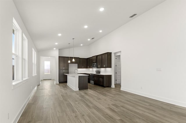 1117 Yaupon Holly Dr, Georgetown, TX 78628 - kitchen featuring light countertops, dark brown cabinetry, open floor plan, a center island with sink, and stainless steel appliances