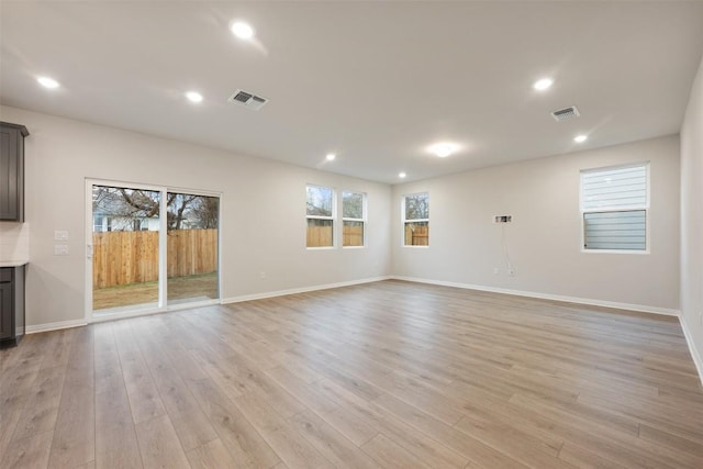 unfurnished living room with light wood-type flooring and a healthy amount of sunlight