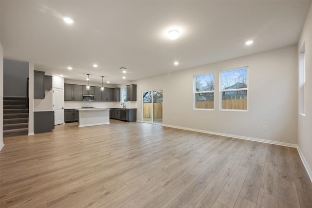 unfurnished living room featuring sink and light hardwood / wood-style flooring