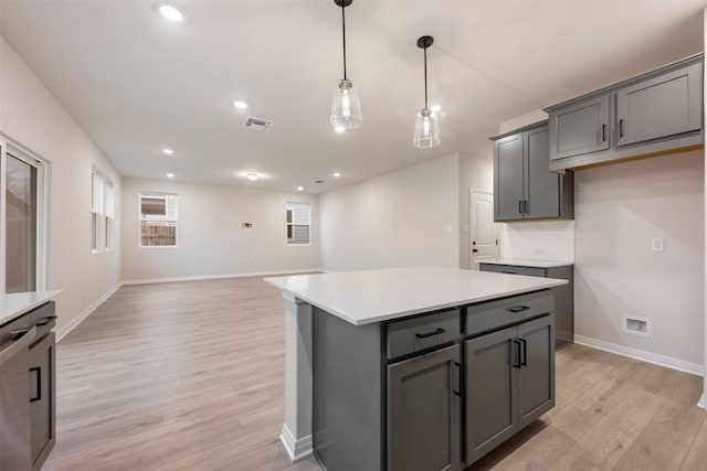 kitchen featuring a kitchen island, gray cabinetry, hanging light fixtures, and light hardwood / wood-style flooring