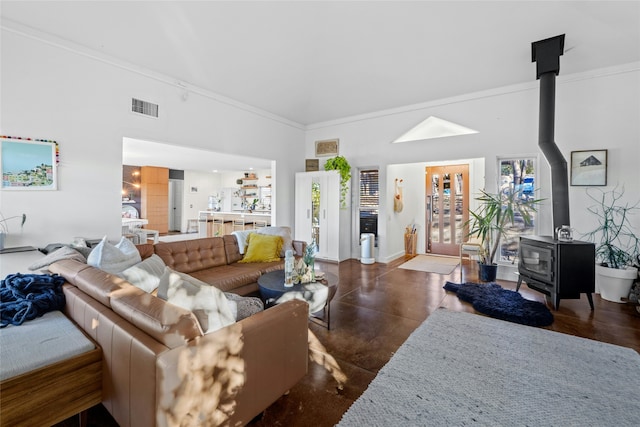 living room with a high ceiling, crown molding, and a wood stove