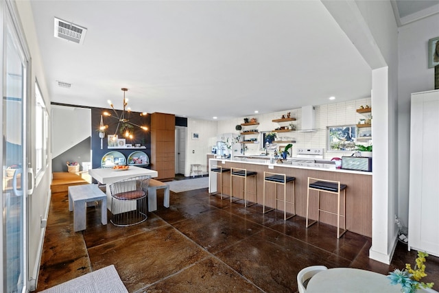 kitchen featuring pendant lighting, a breakfast bar area, backsplash, a center island, and a notable chandelier