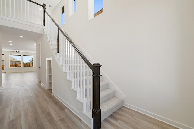 stairs featuring wood-type flooring, ceiling fan, and a high ceiling