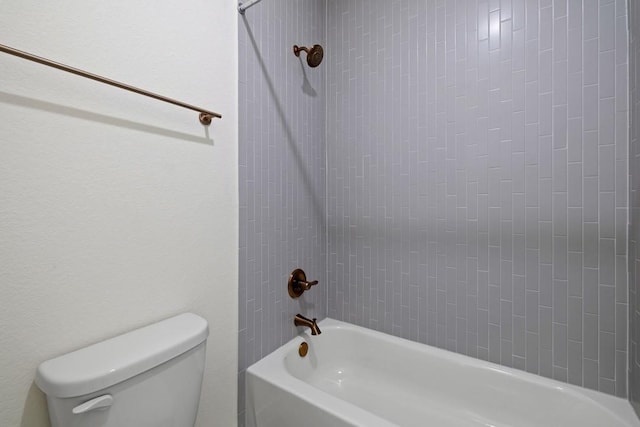 bathroom with tiled shower / bath combo and toilet