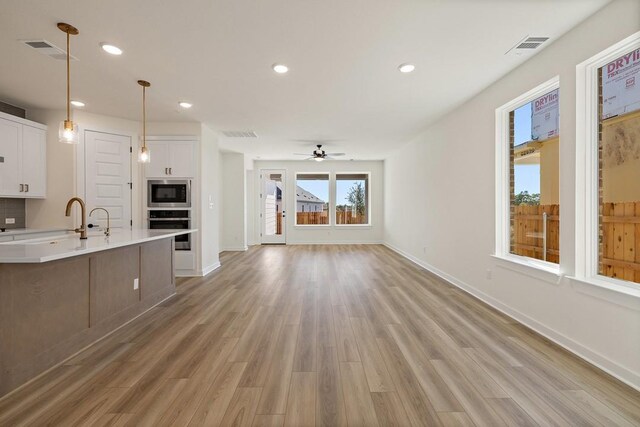 kitchen featuring pendant lighting, ceiling fan, white cabinetry, and stainless steel appliances