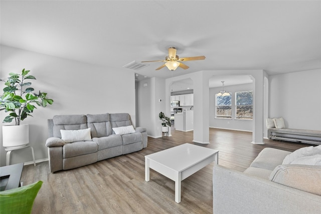 living room with wood-type flooring and ceiling fan with notable chandelier