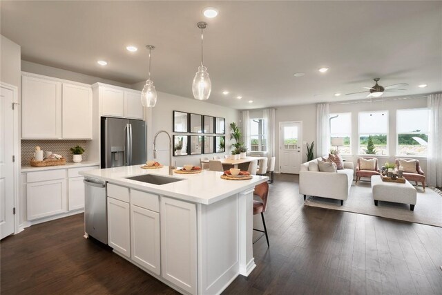 kitchen featuring sink, white cabinets, stainless steel appliances, and a center island with sink