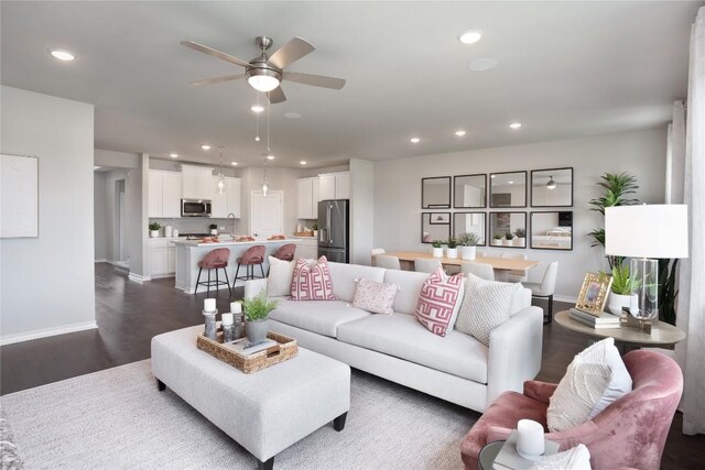 living room featuring ceiling fan, sink, and dark wood-type flooring