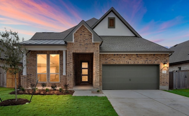 view of front of property featuring metal roof, an attached garage, brick siding, driveway, and a standing seam roof