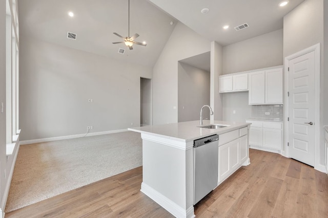 kitchen featuring dishwasher, open floor plan, a kitchen island with sink, white cabinetry, and a sink