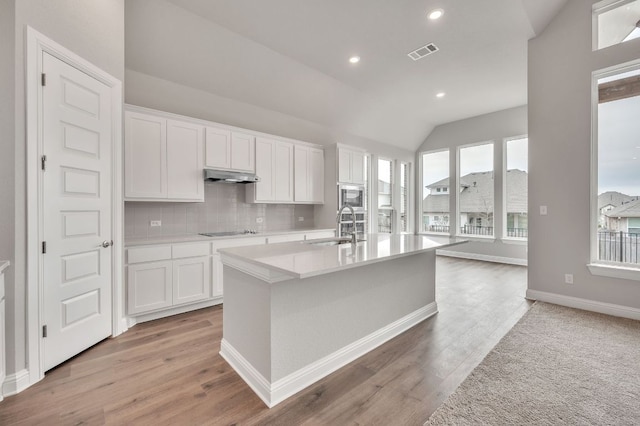 kitchen with light countertops, white cabinetry, and under cabinet range hood