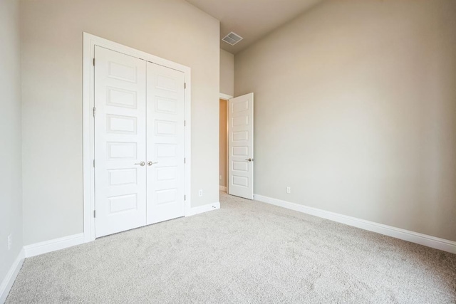 unfurnished bedroom with a closet, visible vents, light carpet, and baseboards