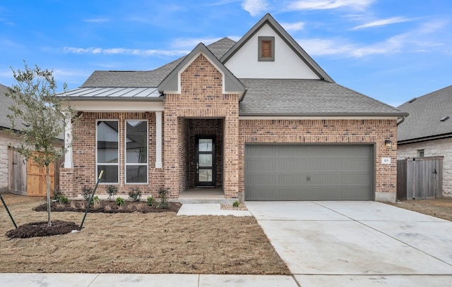 view of front of property featuring brick siding, roof with shingles, concrete driveway, a standing seam roof, and a garage