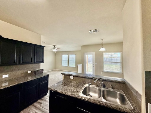 kitchen with pendant lighting, sink, ceiling fan, black dishwasher, and tasteful backsplash