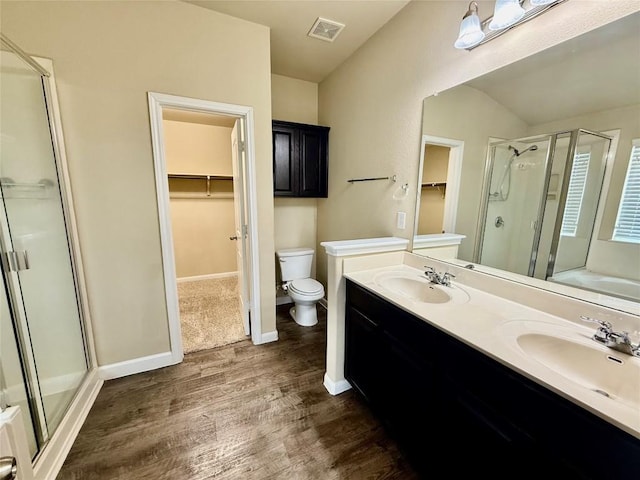 100 Wilson Ct, Hutto, TX 78634 - full bathroom featuring a walk in closet, a stall shower, wood finished floors, double vanity, and vaulted ceiling