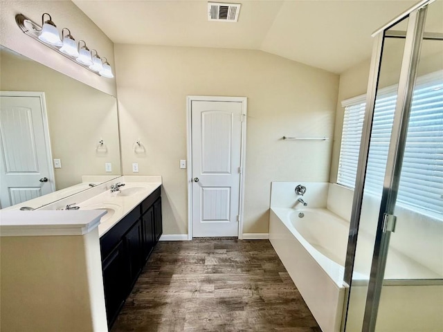 bathroom featuring wood-type flooring, lofted ceiling, vanity, and plus walk in shower