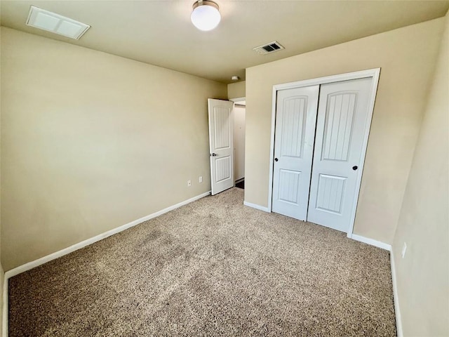 unfurnished bedroom with light colored carpet and a closet