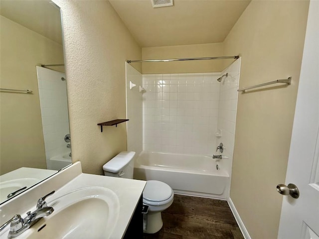 full bathroom featuring hardwood / wood-style flooring, vanity, tiled shower / bath combo, and toilet