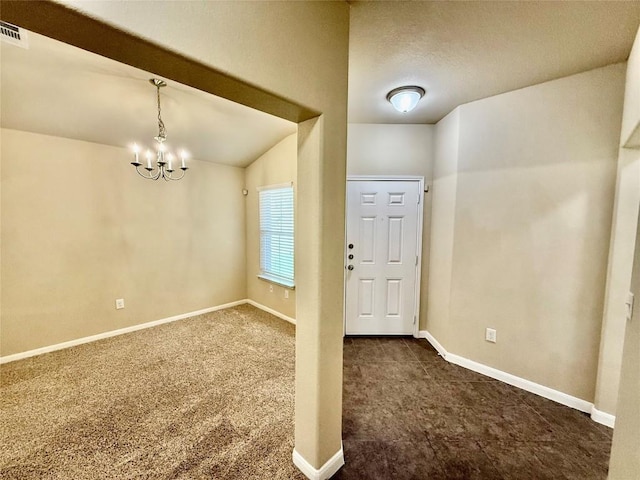 carpeted entrance foyer with lofted ceiling and a chandelier