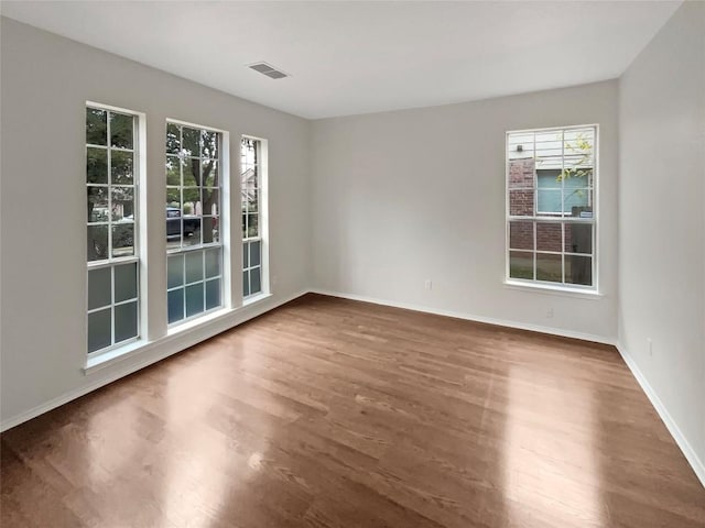 spare room with a healthy amount of sunlight and dark hardwood / wood-style floors