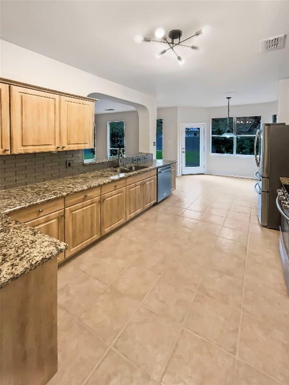 kitchen featuring backsplash, sink, light tile patterned floors, and stainless steel appliances