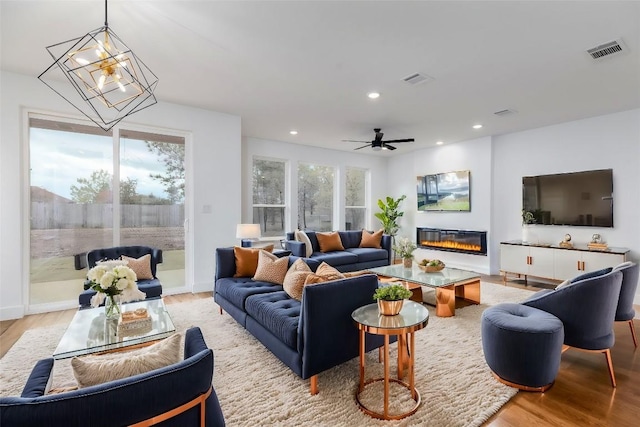 living room featuring light hardwood / wood-style floors and ceiling fan with notable chandelier