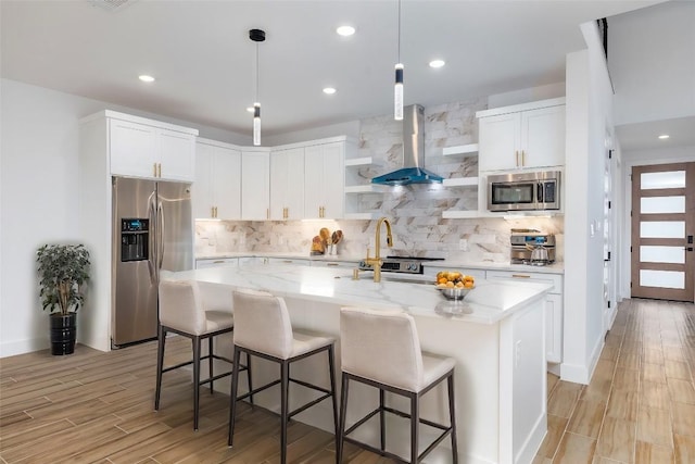 kitchen with light hardwood / wood-style flooring, light stone countertops, an island with sink, white cabinetry, and stainless steel appliances