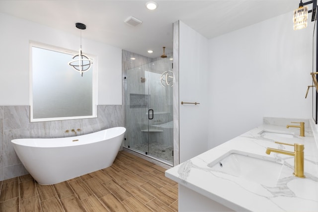 bathroom featuring shower with separate bathtub, vanity, hardwood / wood-style flooring, and tile walls