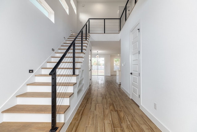 stairs featuring a towering ceiling and hardwood / wood-style flooring