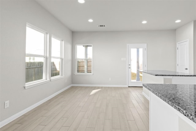 kitchen featuring dark stone countertops, plenty of natural light, white cabinets, and light hardwood / wood-style floors