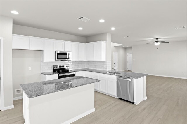 kitchen with a center island, sink, appliances with stainless steel finishes, light hardwood / wood-style floors, and white cabinetry