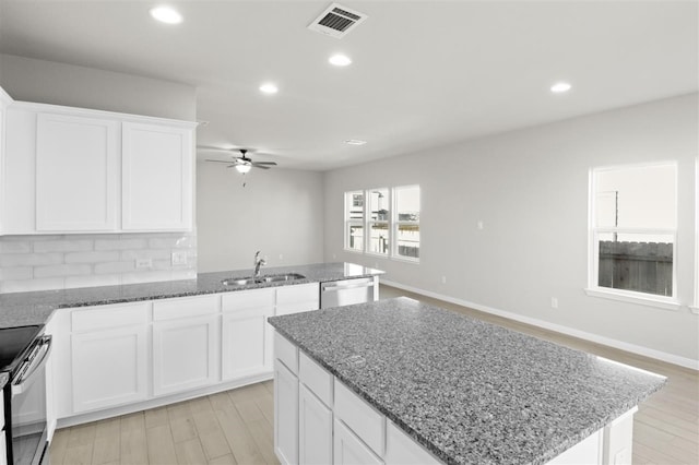 kitchen featuring white cabinets, light wood-type flooring, tasteful backsplash, and ceiling fan