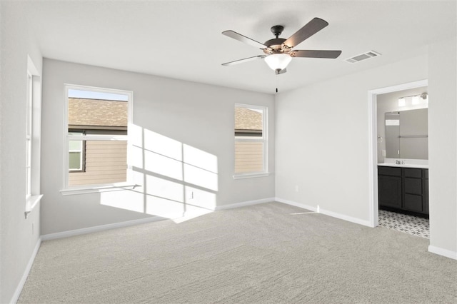 interior space featuring light carpet, ensuite bath, ceiling fan, and sink