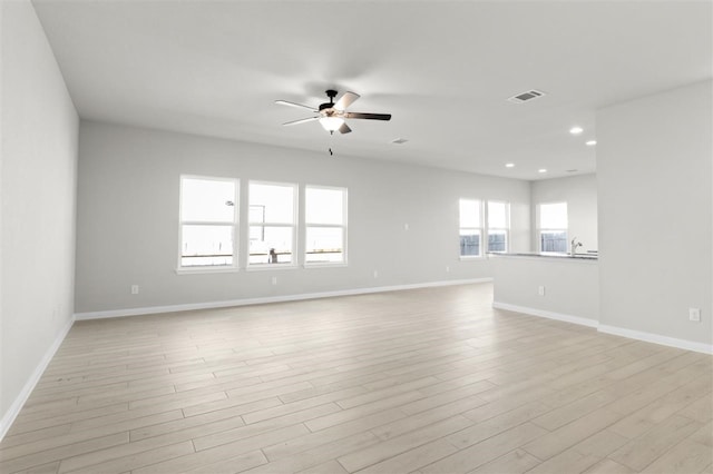 empty room featuring ceiling fan, sink, and light wood-type flooring