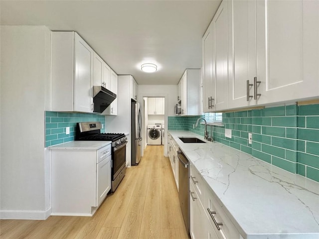 kitchen with white cabinets, sink, light hardwood / wood-style flooring, stainless steel appliances, and washer / clothes dryer