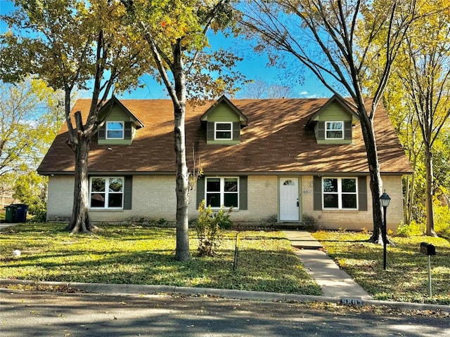 cape cod house featuring a front lawn