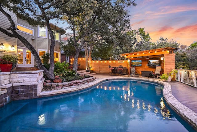 pool at dusk featuring french doors