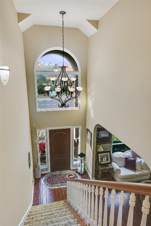 foyer featuring a notable chandelier, wood-type flooring, and high vaulted ceiling