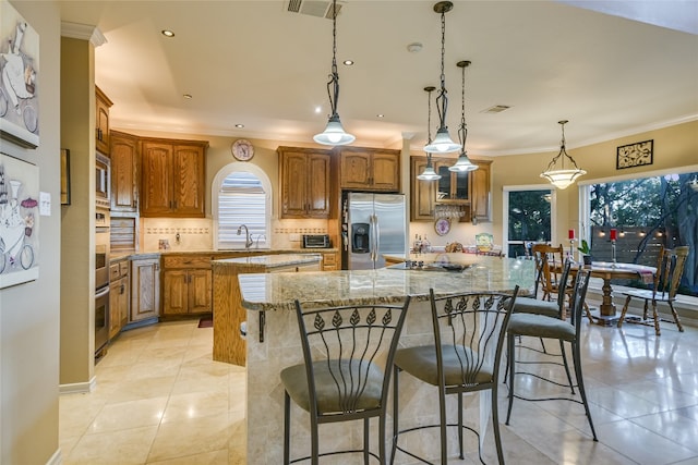 kitchen featuring appliances with stainless steel finishes, light tile patterned floors, pendant lighting, and a kitchen breakfast bar