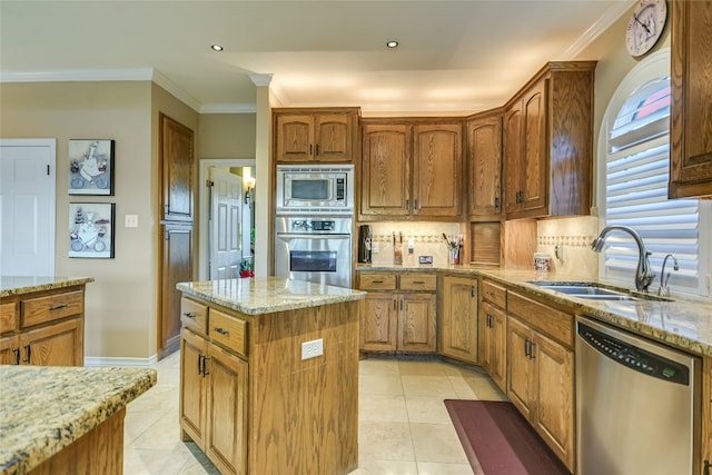 kitchen with decorative backsplash, appliances with stainless steel finishes, light stone counters, sink, and a center island