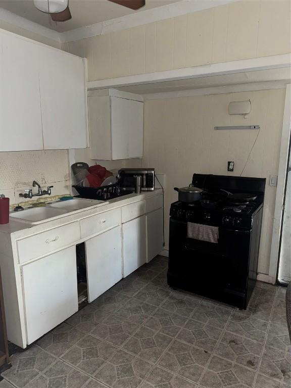 kitchen featuring ceiling fan, black gas stove, white cabinetry, and sink