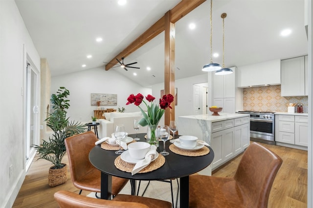 dining area with vaulted ceiling with beams and light hardwood / wood-style flooring