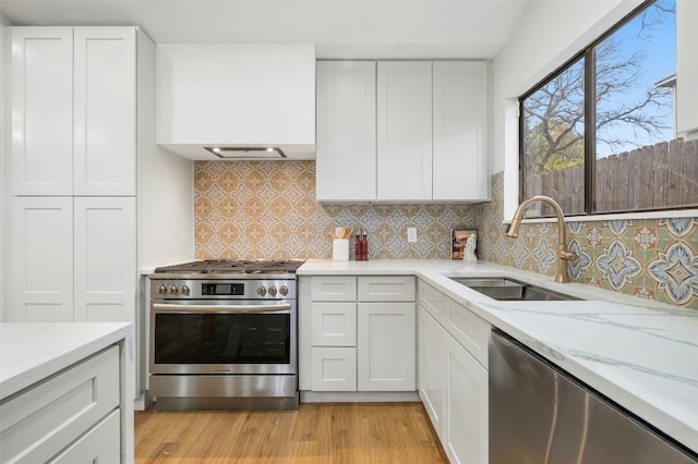 kitchen featuring white cabinetry, sink, stainless steel appliances, and light stone countertops