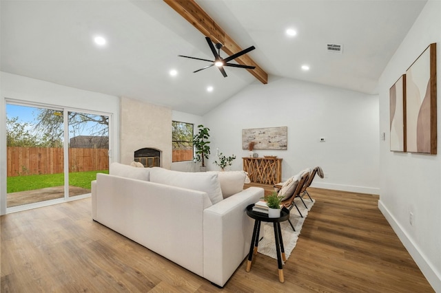 living room with hardwood / wood-style flooring, a large fireplace, ceiling fan, and vaulted ceiling with beams