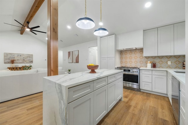 kitchen with appliances with stainless steel finishes, white cabinets, hanging light fixtures, light stone counters, and light hardwood / wood-style flooring