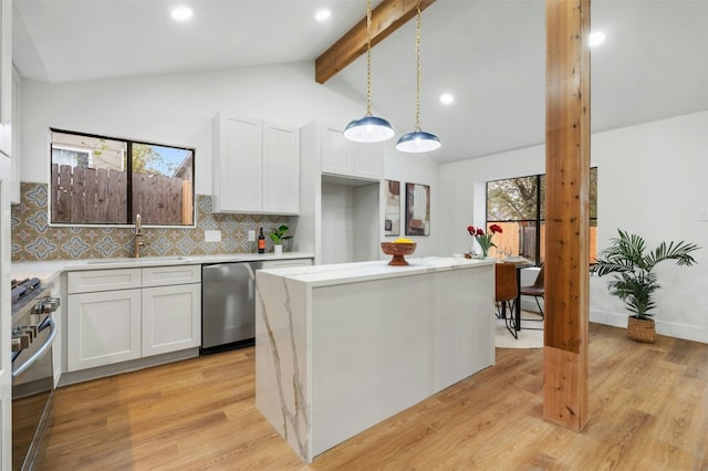 kitchen with sink, hanging light fixtures, stainless steel appliances, a center island, and white cabinets