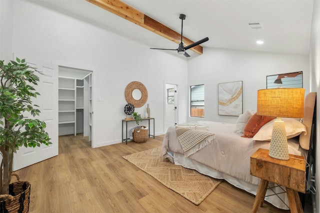 bedroom with a spacious closet, lofted ceiling with beams, ceiling fan, and light wood-type flooring