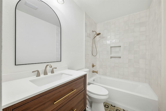 full bathroom featuring tiled shower / bath, vanity, and toilet