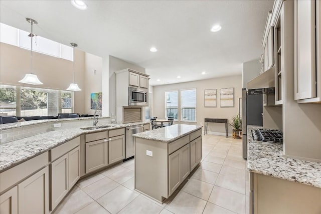 kitchen with stainless steel appliances, sink, light tile patterned floors, a kitchen island, and hanging light fixtures